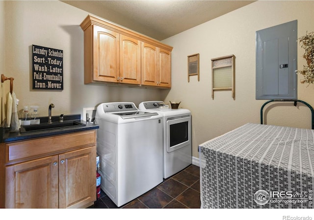 washroom featuring electric panel, dark tile patterned floors, a sink, cabinet space, and washer and clothes dryer