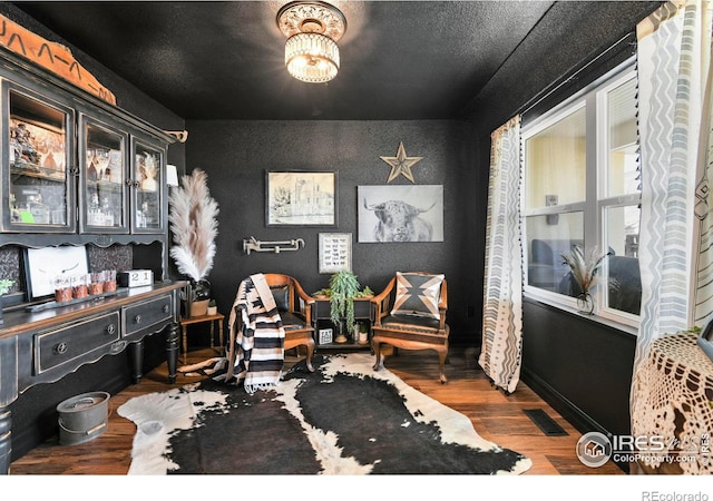 interior space featuring visible vents, baseboards, a textured ceiling, wood finished floors, and wallpapered walls