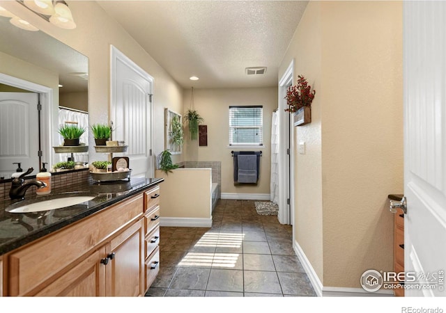 bathroom with vanity, baseboards, tile patterned flooring, a textured ceiling, and visible vents