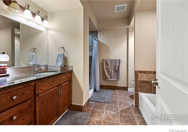 bathroom featuring vanity, baseboards, a shower stall, visible vents, and a bath