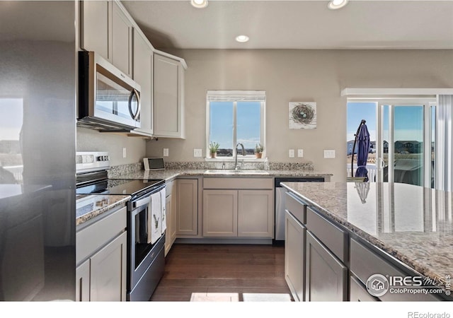 kitchen with stainless steel appliances, dark wood-style floors, a sink, recessed lighting, and light stone countertops