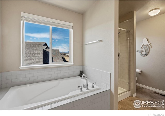 full bathroom with a shower stall, a garden tub, baseboards, and toilet