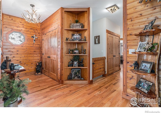 9512 County Road 43, Glen Haven, CO 80532 - hall with light wood-style flooring, wood walls, and an inviting chandelier
