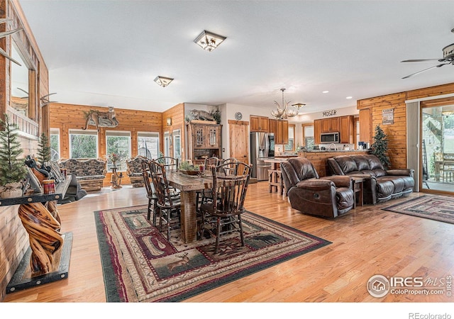 9512 County Road 43, Glen Haven, CO 80532 - dining room with wooden walls, light wood-style flooring, and ceiling fan with notable chandelier