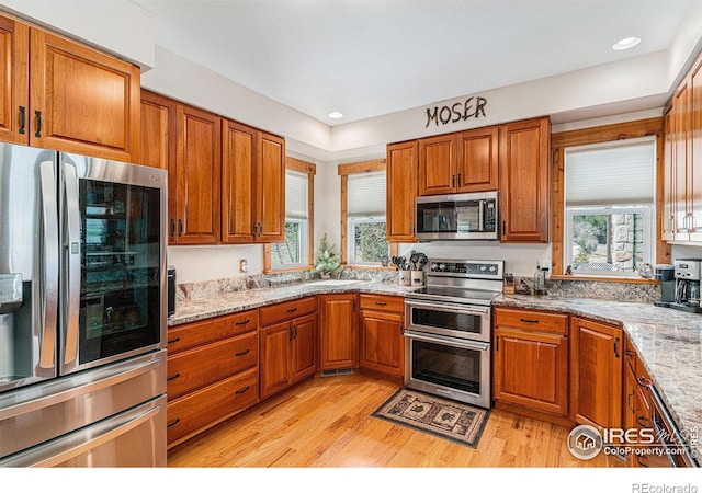 9512 County Road 43, Glen Haven, CO 80532 - kitchen with light wood-style flooring, brown cabinetry, light stone countertops, and stainless steel appliances