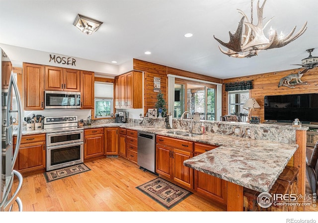 9512 County Road 43, Glen Haven, CO 80532 - kitchen with light wood-type flooring, appliances with stainless steel finishes, a peninsula, brown cabinetry, and a sink