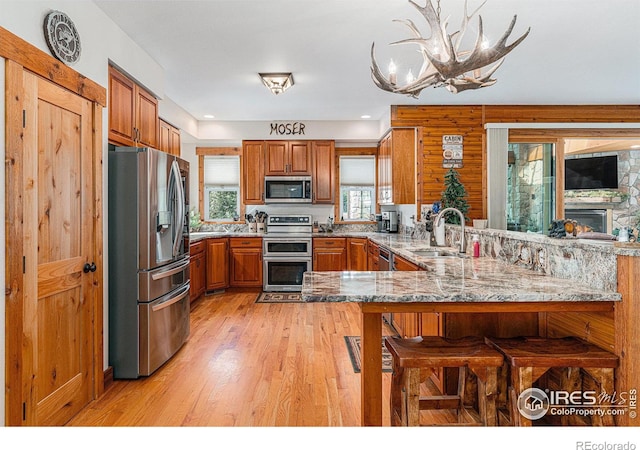 9512 County Road 43, Glen Haven, CO 80532 - kitchen with light wood-type flooring, a sink, stainless steel appliances, a peninsula, and brown cabinetry