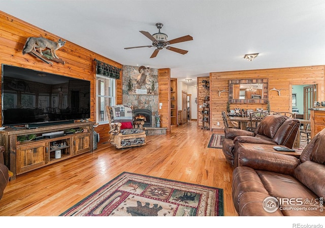 9512 County Road 43, Glen Haven, CO 80532 - living room with a stone fireplace, wood finished floors, wooden walls, and a ceiling fan