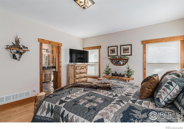 9512 County Road 43, Glen Haven, CO 80532 - bedroom featuring visible vents, baseboards, ensuite bath, and wood finished floors