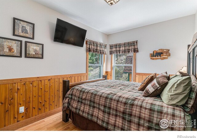 9512 County Road 43, Glen Haven, CO 80532 - bedroom with wooden walls, wood finished floors, and wainscoting