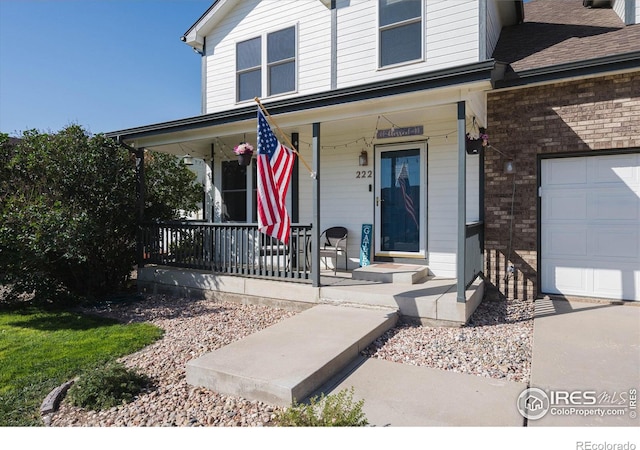 doorway to property with a garage, brick siding, and covered porch
