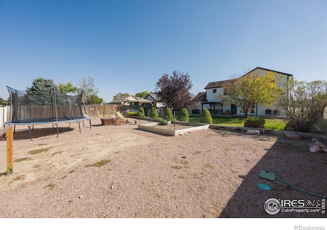 view of yard featuring a vegetable garden, a trampoline, and fence