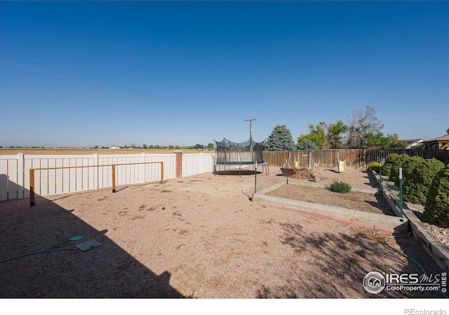 view of yard with a trampoline and a fenced backyard