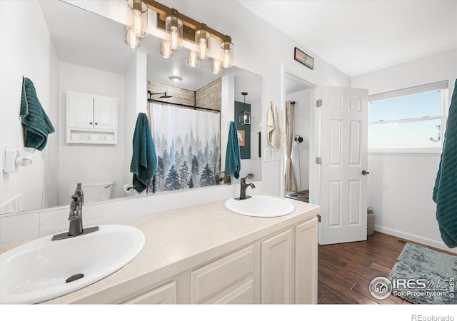 full bath with a sink, a shower with curtain, wood finished floors, and double vanity