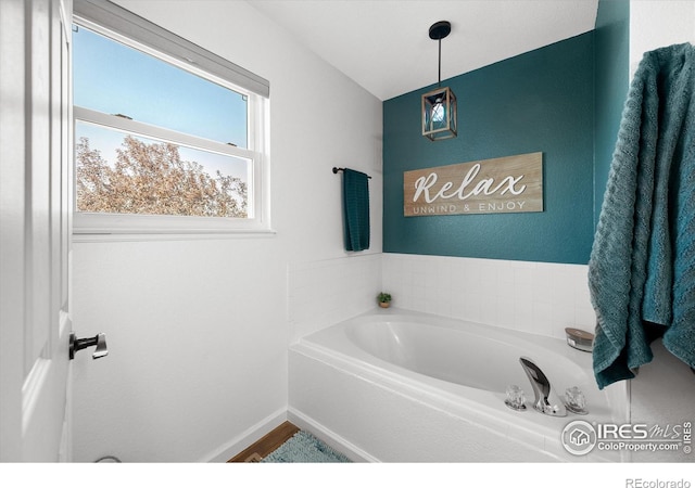 full bathroom with a bath and baseboards