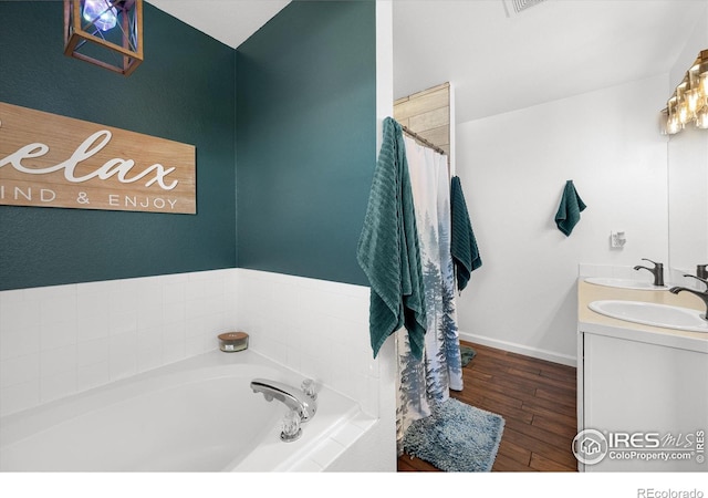 bathroom with a bath, wood finished floors, baseboards, and a sink