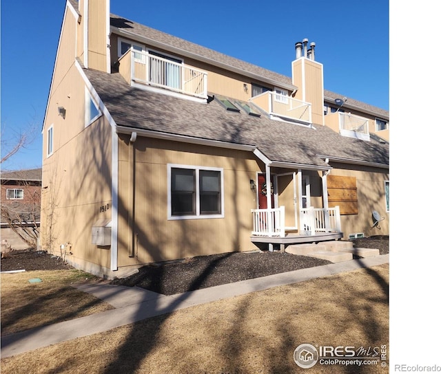 1512 12th Ave Unit 1, Greeley, CO 80631 - back of house featuring a balcony, a shingled roof, covered porch, and a chimney