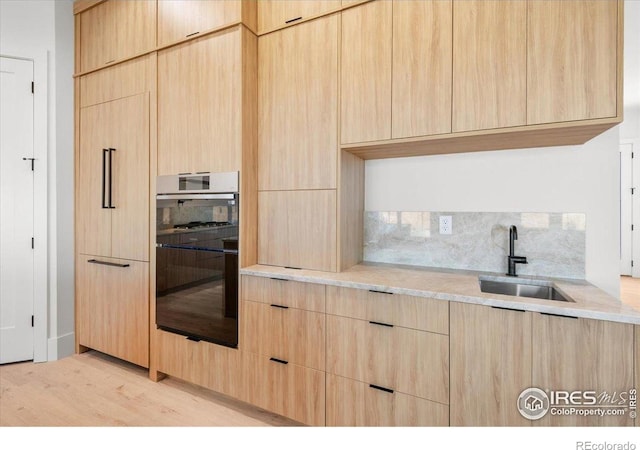 kitchen featuring light brown cabinets, a sink, decorative backsplash, and modern cabinets