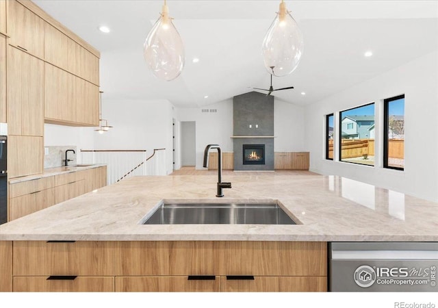 kitchen with a sink, light brown cabinetry, modern cabinets, vaulted ceiling, and recessed lighting