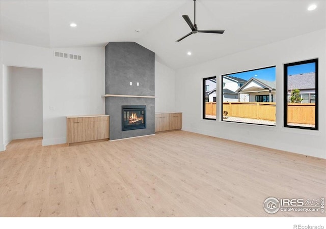 unfurnished living room with wood finished floors, plenty of natural light, vaulted ceiling, ceiling fan, and a fireplace