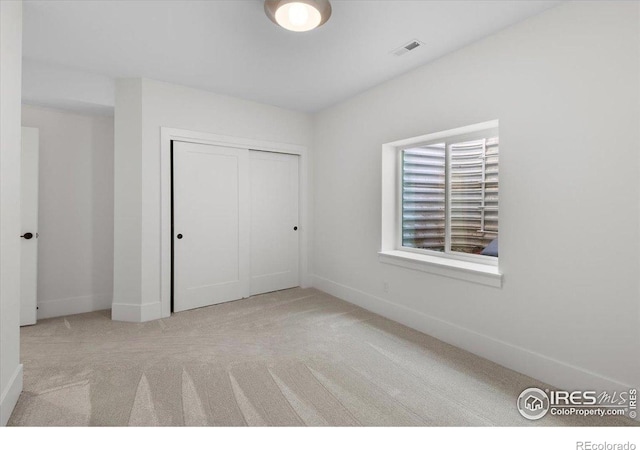 unfurnished bedroom with carpet flooring, baseboards, and a closet