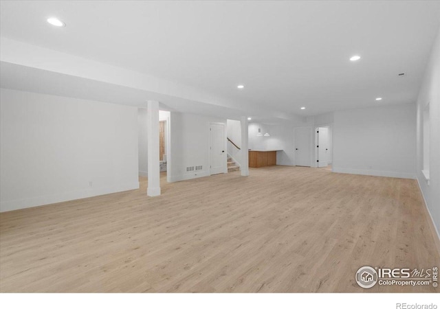 finished basement with light wood-type flooring, recessed lighting, stairway, and baseboards