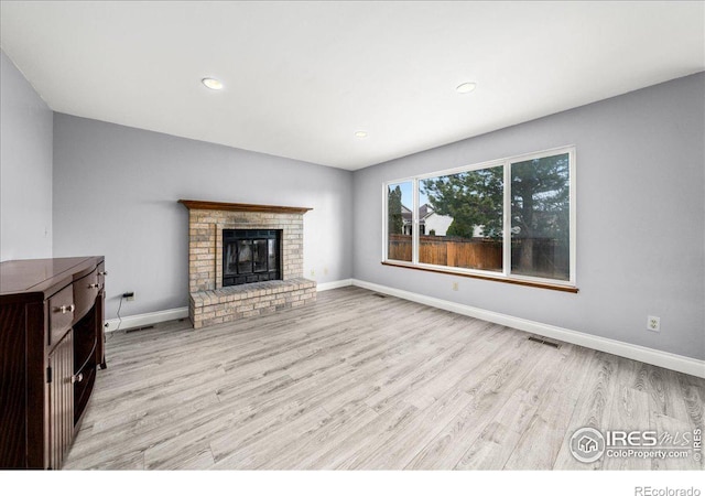 660 Fernglen Ct, Colorado Springs, CO 80906 - unfurnished living room featuring a brick fireplace, wood finished floors, visible vents, and baseboards