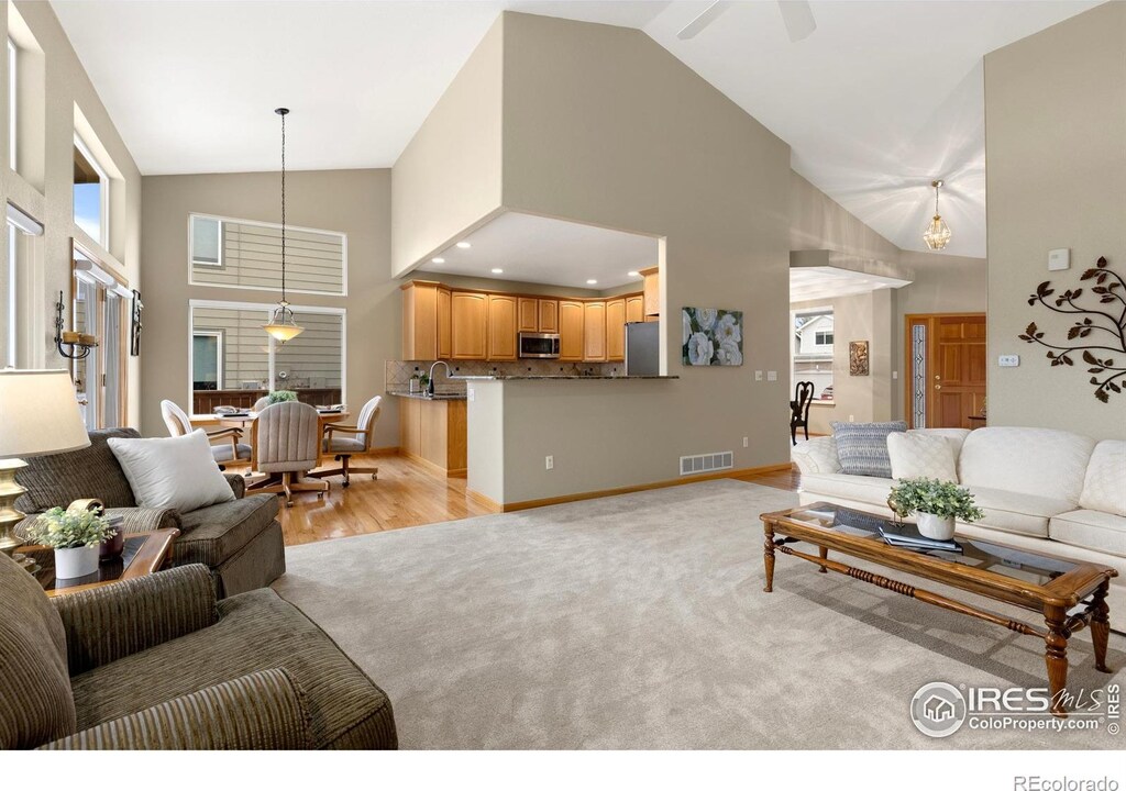 735 Orchard Ct, Louisville, CO 80027 - living area with visible vents, baseboards, light carpet, high vaulted ceiling, and a ceiling fan