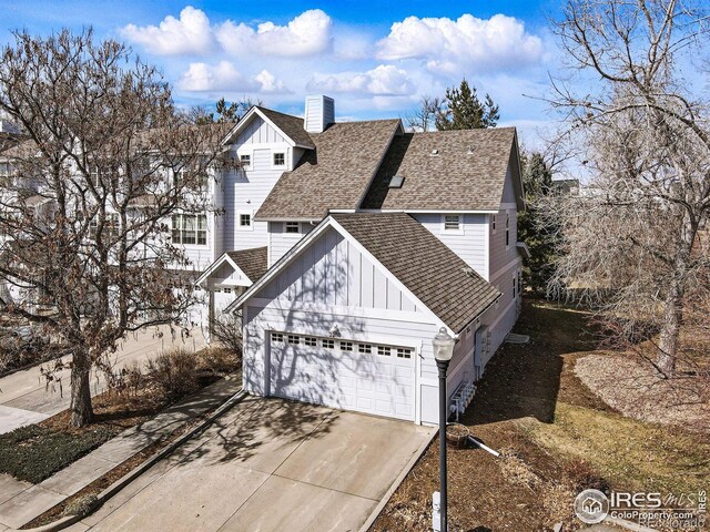 traditional home featuring a chimney, an attached garage, concrete driveway, and roof with shingles
