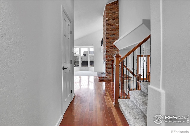 10895 W Half Moon Pass, Littleton, CO 80127 - entrance foyer with a textured wall, wood-type flooring, vaulted ceiling, stairway, and baseboards