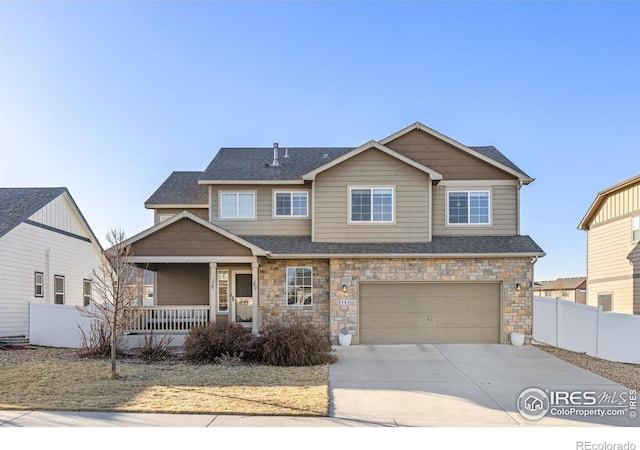 view of front of property featuring fence, a porch, an attached garage, concrete driveway, and stone siding
