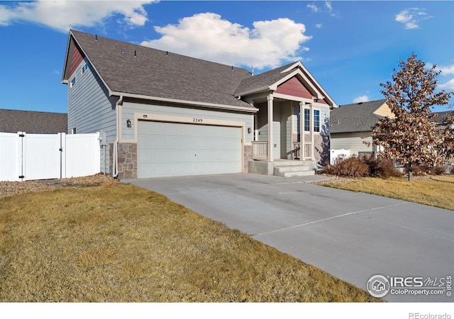 view of front of house featuring a gate, fence, an attached garage, concrete driveway, and a front lawn