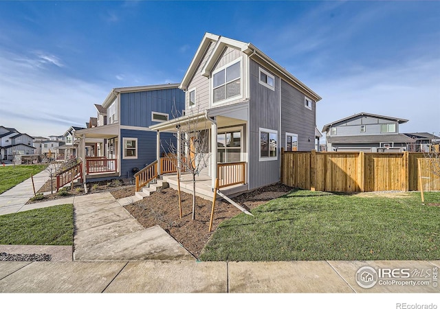 view of front facade with board and batten siding, a front lawn, and fence