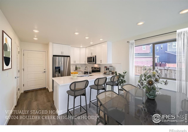 kitchen featuring a sink, white cabinetry, stainless steel appliances, a peninsula, and light countertops