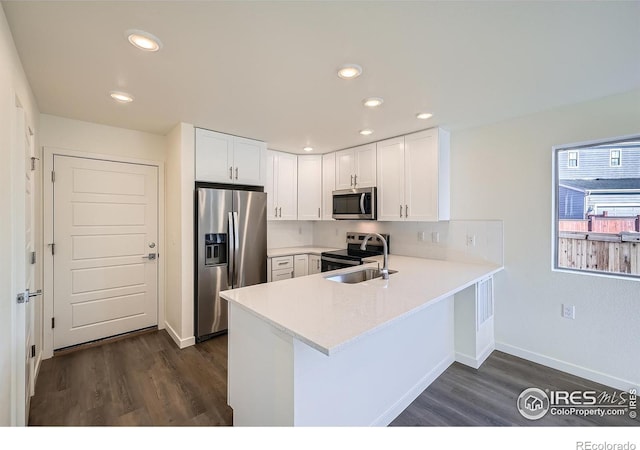 kitchen featuring appliances with stainless steel finishes, a peninsula, light countertops, and white cabinetry