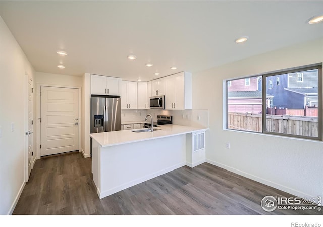 kitchen featuring a sink, a peninsula, appliances with stainless steel finishes, white cabinets, and light countertops