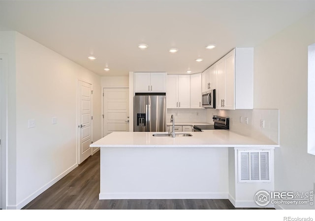 kitchen with visible vents, light countertops, a peninsula, stainless steel appliances, and a sink