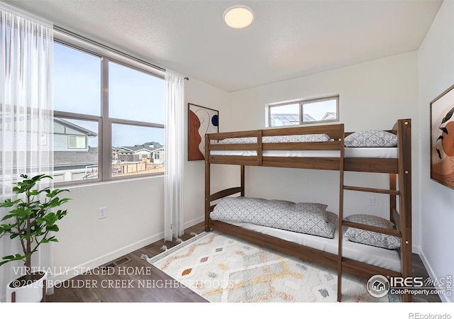 bedroom with visible vents, baseboards, and wood finished floors