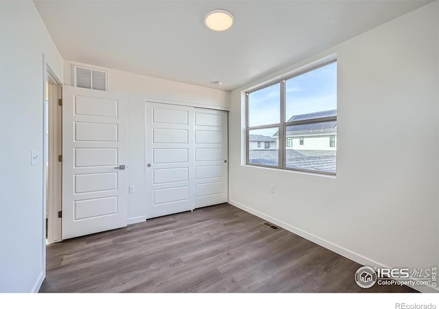 unfurnished bedroom with visible vents, baseboards, a closet, and wood finished floors