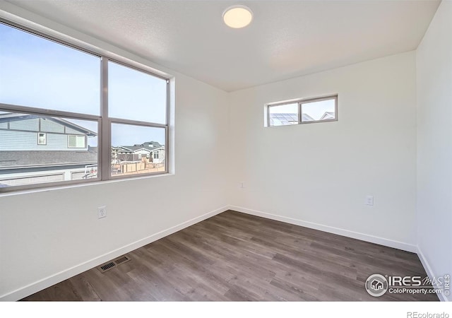 unfurnished room featuring visible vents, baseboards, and wood finished floors