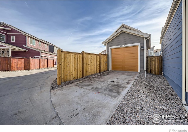 garage with concrete driveway and fence
