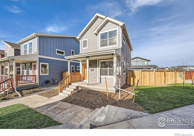 view of front of property with a porch, fence, board and batten siding, and a front yard