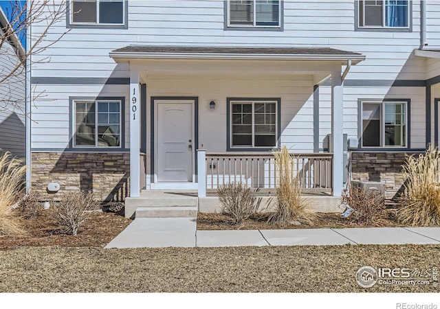 entrance to property with stone siding and a porch