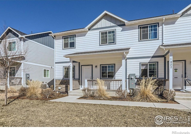 townhome / multi-family property with stone siding, covered porch, and board and batten siding