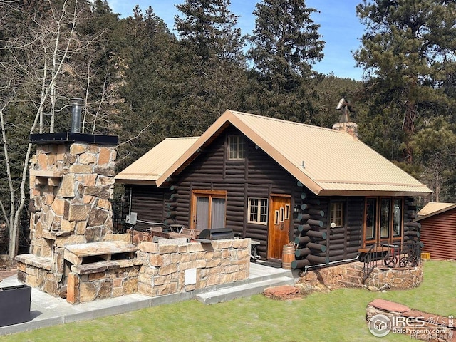 rear view of house featuring a chimney, metal roof, and log siding