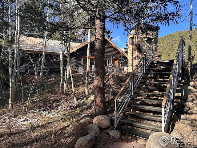 view of home's exterior with stairs and metal roof