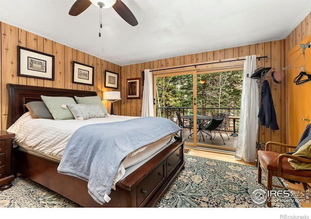 bedroom featuring ceiling fan, wooden walls, light wood-type flooring, and access to exterior