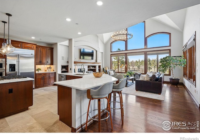 kitchen with a sink, open floor plan, stainless steel appliances, a breakfast bar area, and a fireplace