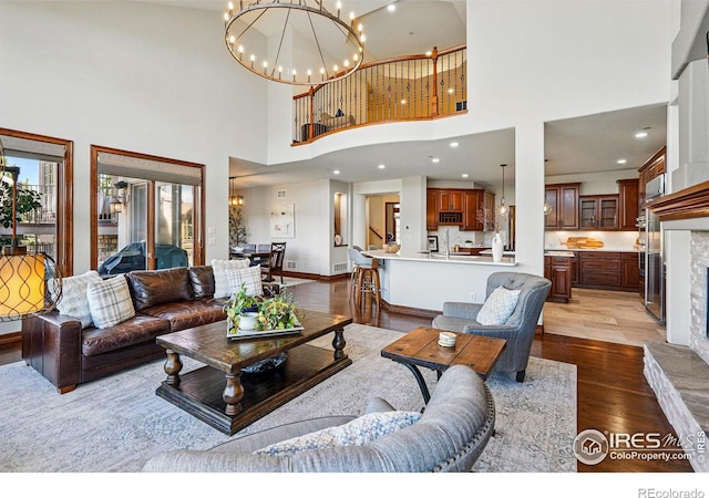 living room with visible vents, baseboards, recessed lighting, an inviting chandelier, and wood finished floors