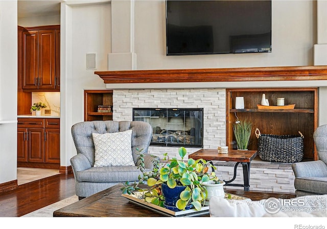 living area featuring a stone fireplace and wood finished floors